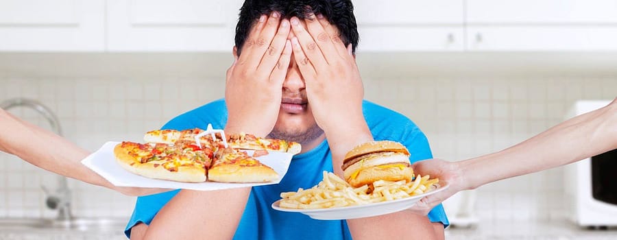 Weight Loss Hypnotherapy - In this image provided by the client, a man tries to avoid unhealthy food choices. He can be seen with his eyes closed, as he visualizes his success in achieving his weight loss goals through our proven techniques.